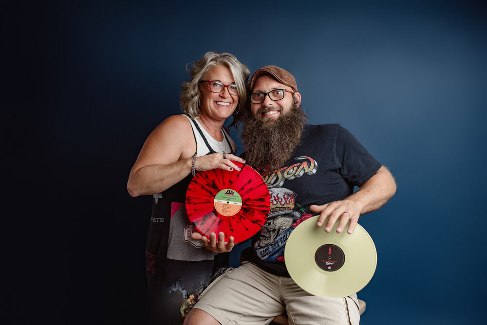 The owners of Blind Guy Records holding up vinyl records